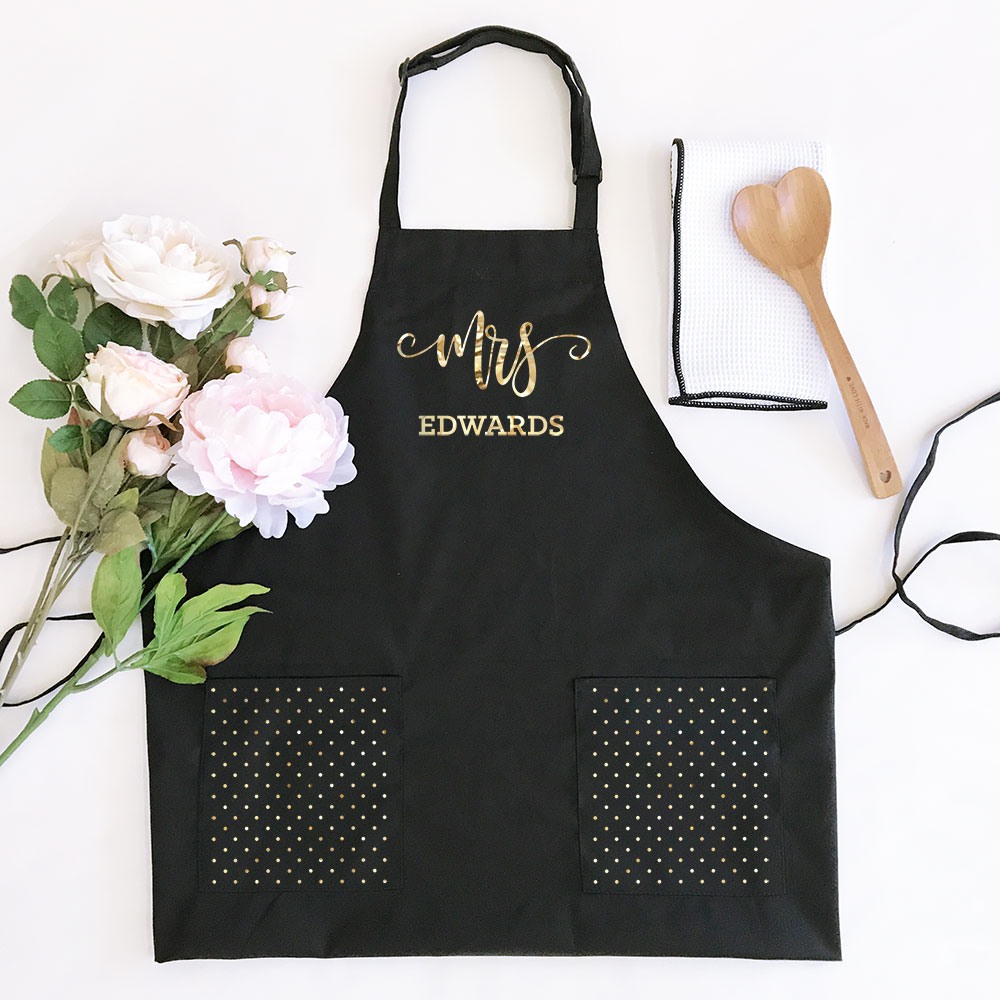 Woman's black apron is personalized with the bride's new last name, for a unique bridal shower gift.